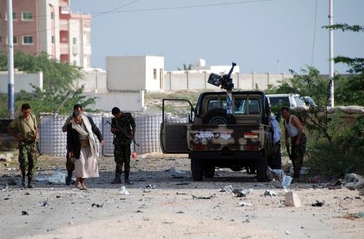 Les forces de sécurité yéménites sont vus le long d'une route principale jonchée de débris après un kamikaze a fait exploser un véhicule à l'extérieur d'un palais présidentiel à Mukalla le Février 25, 2012